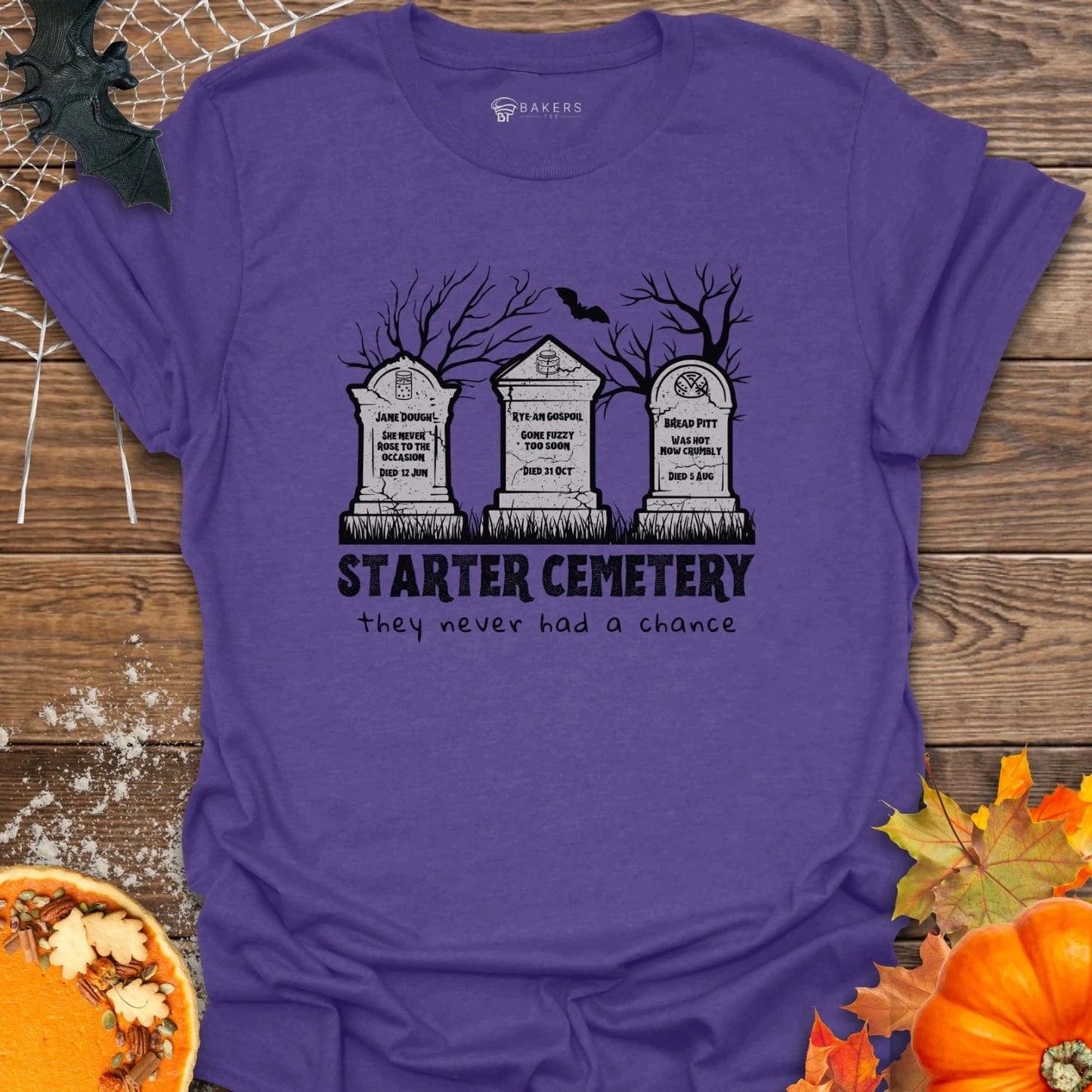 Heather Purple t-shirt with 'Starter Cemetery' design on a wooden surface with Halloween decorations.