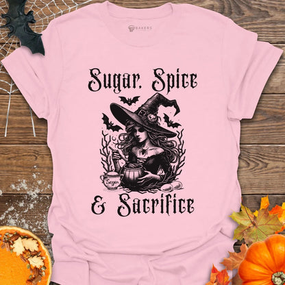 Pink t-shirt with Halloween-themed design featuring a witch and text on a wooden background with pumpkins and leaves.
