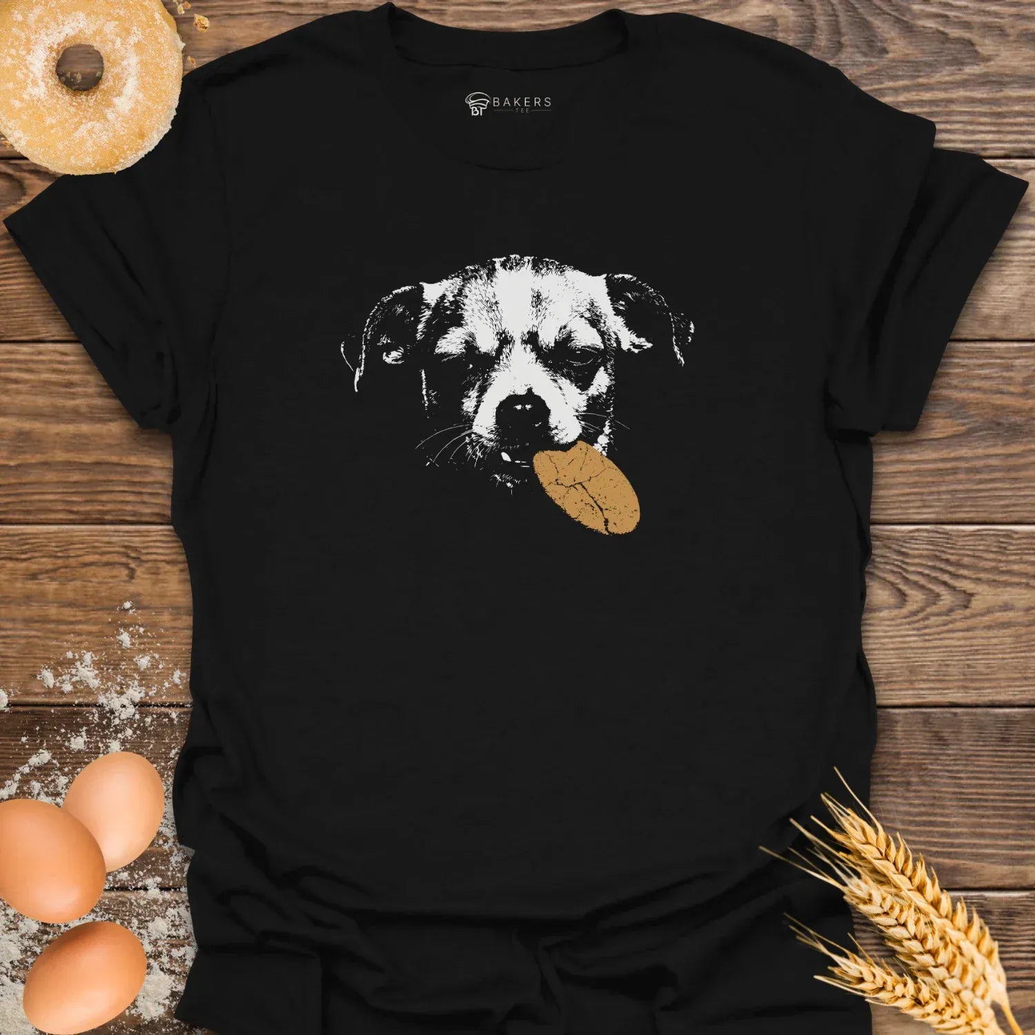 Black t-shirt featuring a white graphic of a dog holding a brown cookie in its mouth.