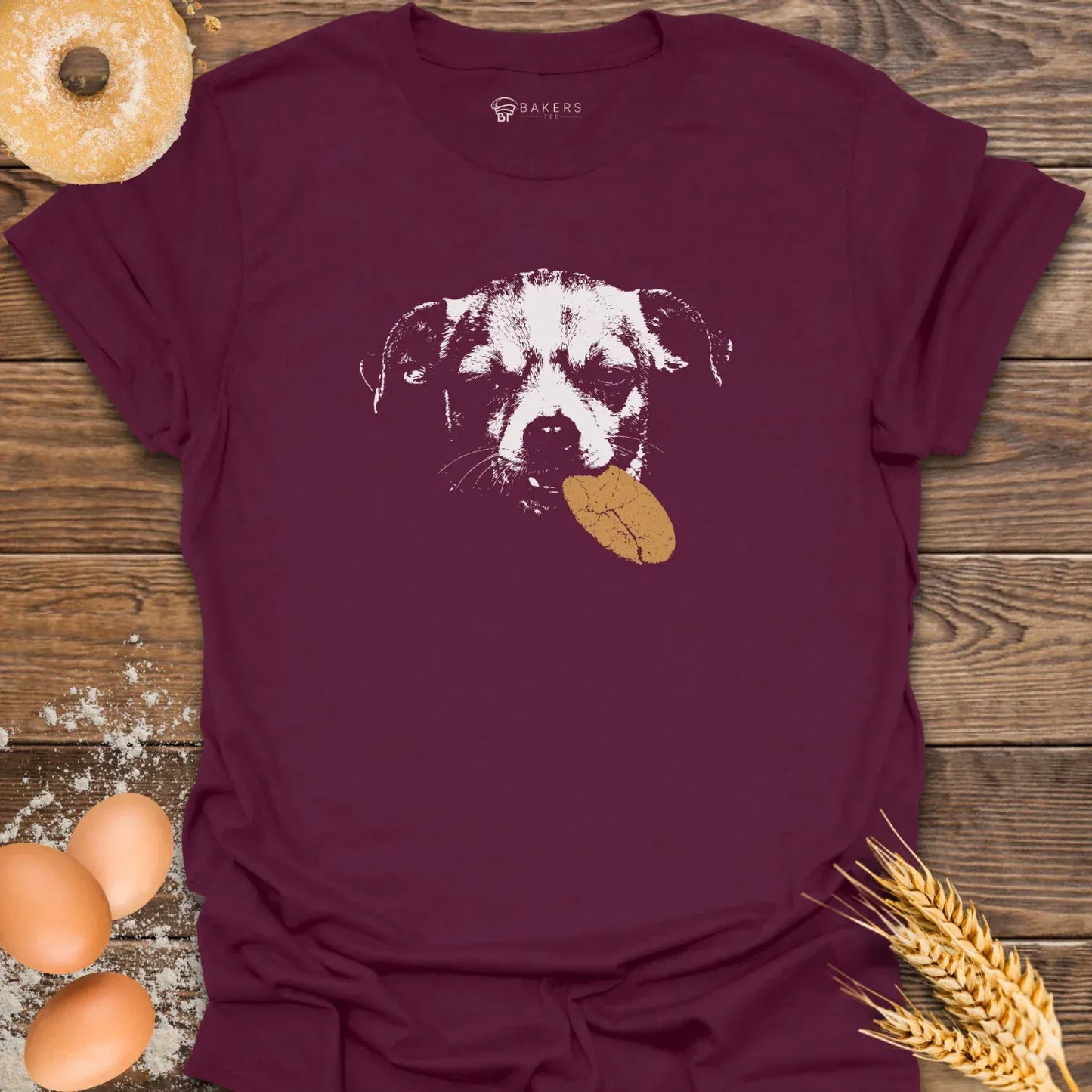 Maroon t-shirt featuring a white graphic of a dog holding a brown cookie in its mouth.